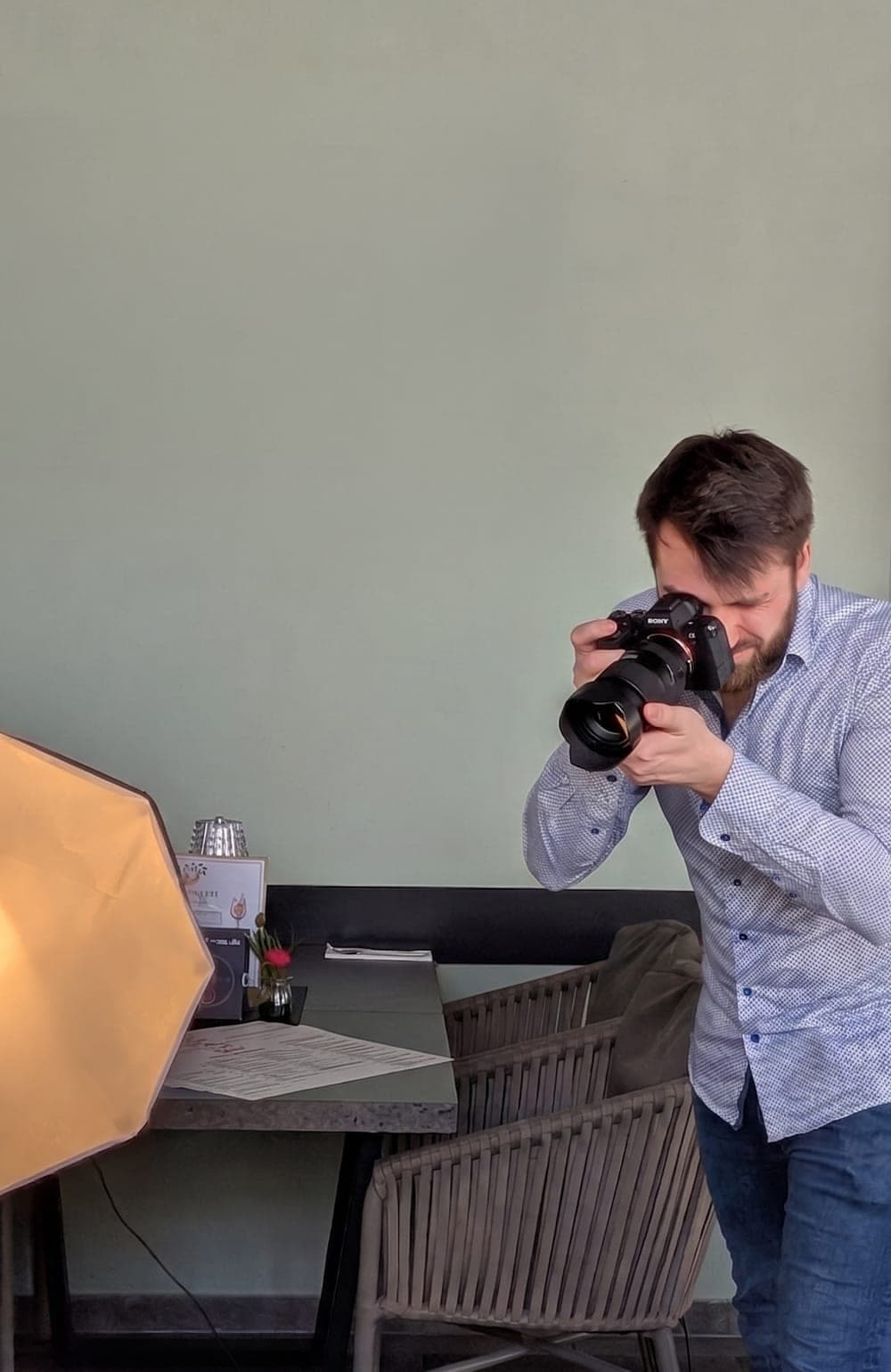 Jonas fotografiert mit Kamera und Studiolicht in einem Restaurant