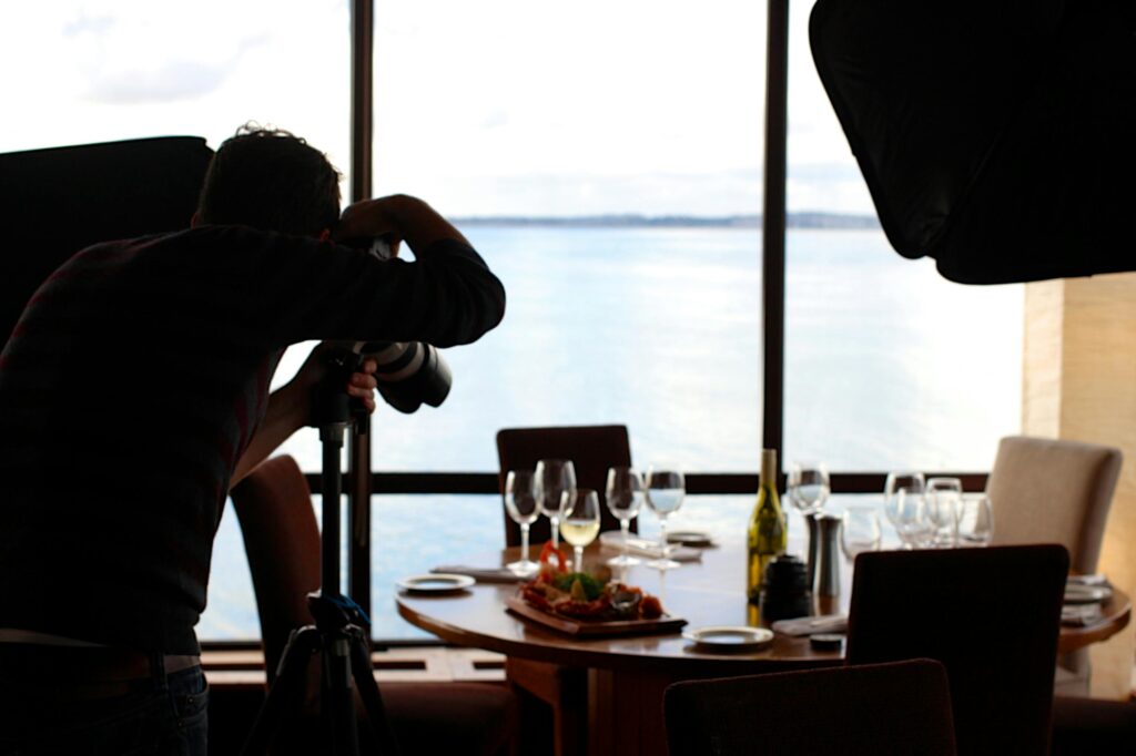 food restaurant camera taking photo 3022 2 Photographer shoots a beautifully arranged restaurant table by the sea. Elegant setup with food and wine.